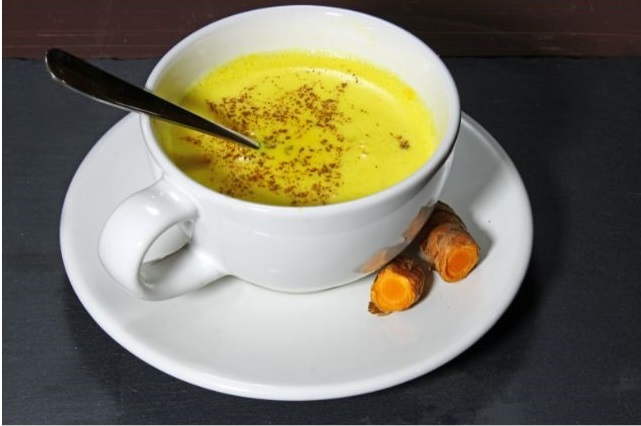 A close-up of a mug filled with warm golden milk with a hint of turmeric and cinnamon. A perfect healthy and comforting drink