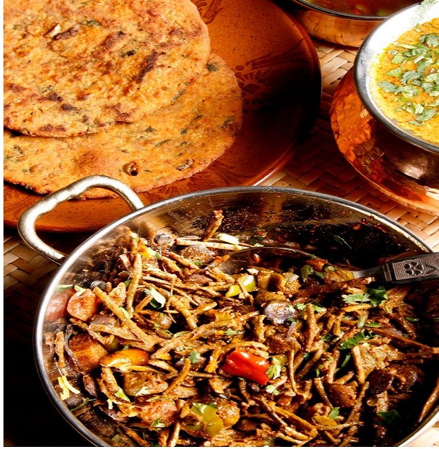 A plate of Ker Sangri, a traditional Rajasthani dish made with a combination of dried wild berries and beans, served with roti on the side. The dish is known for its unique and robust flavor, and is often considered a comfort food in Rajasthan